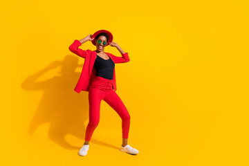 Fototapeta na wymiar Photo of beautiful excited short hair person dressed red suit cap dark glasses dancing empty space isolated yellow color background