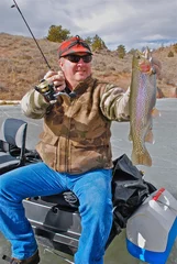 Tuinposter Ice fisherman with a rainbow trout  © Verbbaitum