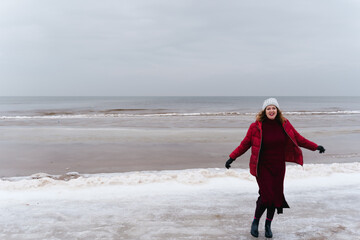 Fototapeta na wymiar Smiling woman runs along the seashore in winter