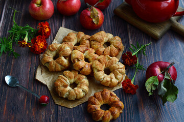 Closeup of homemade pastries with apples and cinnamon on a dark wooden background. View from above