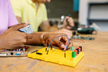 Close up female student hands creating electronic circuits and robotics at technology class