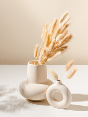 Ceramic beige vase aesthetic composition with dry lagurus grass and shadows. Minimal boho interior...