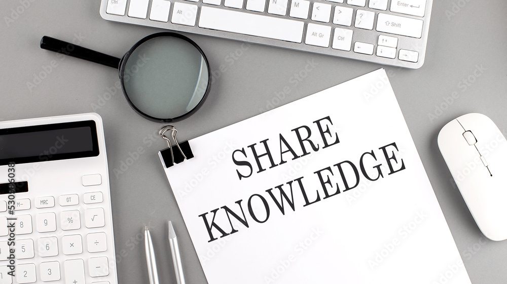 Aufkleber share knowledge written on paper with office tools and keyboard on the grey background