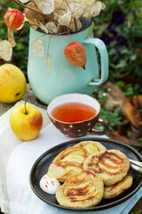 Whole wheat apple pancakes served with tea in the garden. Rustic style.