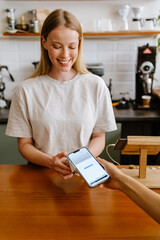 Blonde white barista woman working with terminal in cafe