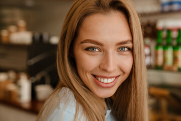 Blonde young waitress woman smiling while working at cafe