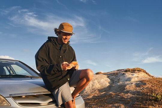 Handsome young man using mobile phone while sitting at the car