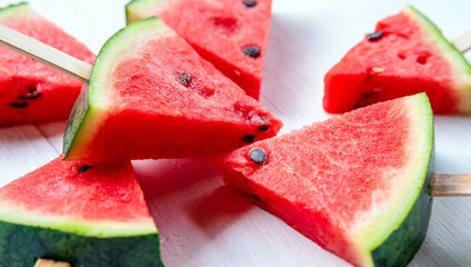 Close up of watermelon slice popsicles on white wooden background