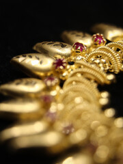 closeup shot of an antique golden jewelry necklace with precious red stones isolated on a black background