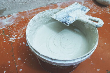 bucket with plaster and spatula, interior repair and wall alignment