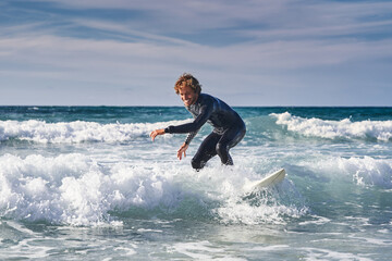 Surfing man enjoying waves at the cold ocean water while training during the summer