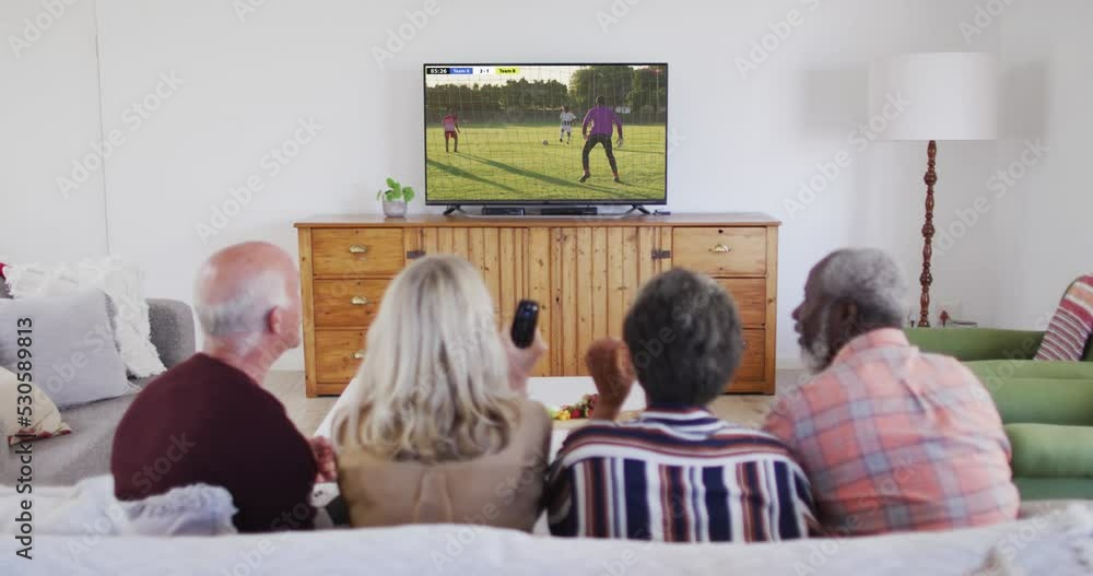 Wall mural Video of diverse group of senior people sitting on the couch and watching football match