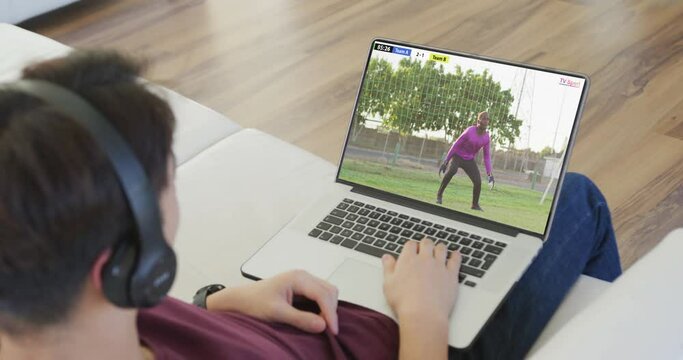 Video of person sitting on the couch and watching football match on laptop