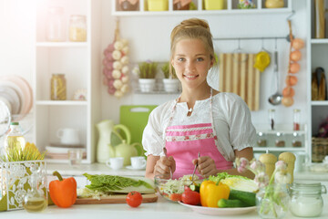 Obraz na płótnie Canvas Beautiful girl preparing a salad in the kitchen