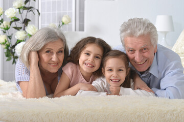 Grandparents and grandchildren lie on the bed 