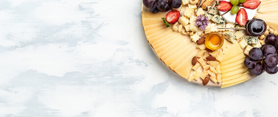 Antipasto Cheese board of various types of soft and hard cheese on a light background. Long banner...