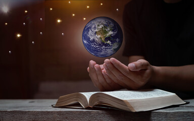 A man read the bible while lay hand and praying on blurred world globe. christian prayer concept,...