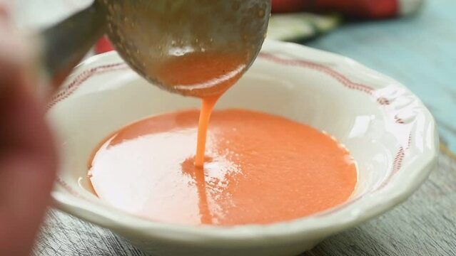 Serving the cold tomato soup in the plate.
