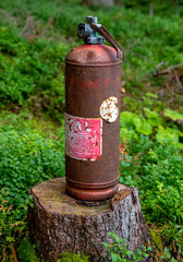 old and rusty fire extinguisher on a tree stump in a forest, Austria