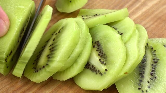 The cook cuts pieces of a kiwi.