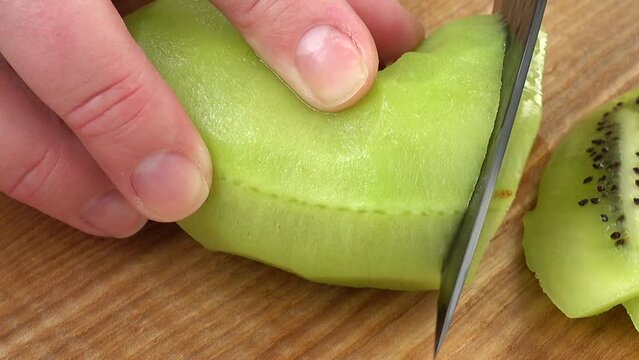 The cook cuts pieces of a kiwi.