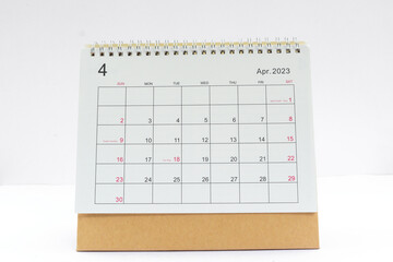 april 2023 Desktop calendar for planners and reminders on a wooden table on a white background.