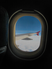 Fototapeta na wymiar View from the cabin into the porthole on the wing of the cloud and the sky at a height during the flight 