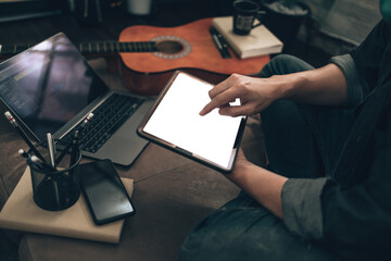  Music creator create melody song, lyrics on laptop and tablet while sitting on sofa bed in living room at home.
