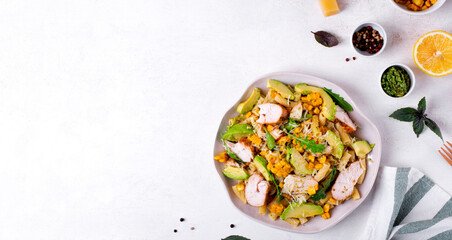 Pasta salad with chicken, avocado, grilled corn, cheese, arugula and pesto sauce served on the white plate. Copy space