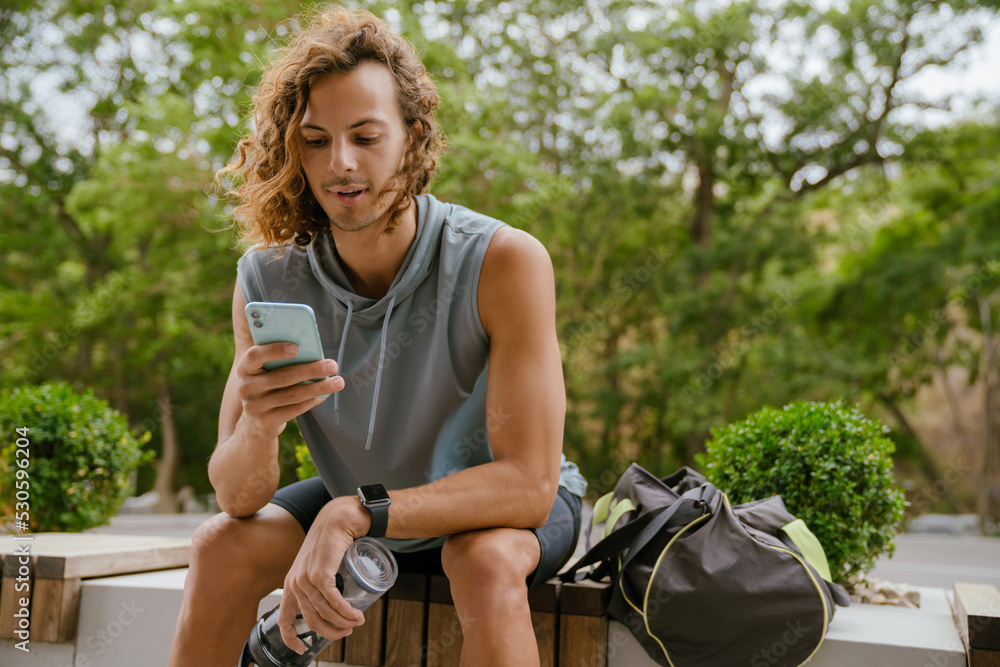 Poster portrait of young long-haired athletic man holding phone