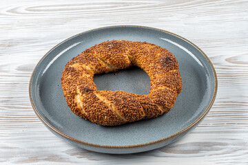 Simit or gevrek, traditional Turkish pastry food on the white wooden background. Turkish street food circular bread, bagel with sesame.