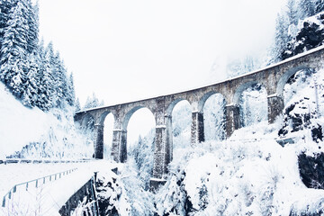Mountain landscape with Sainte Marie bridge covered with snow in Les Houches, Chamonix valley, Eastern France. Viaduct bridge built to carry a railway over water.