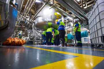 Blur male worker repairs stainless vertical steel tanks with equipment tank chemical cellar at the...