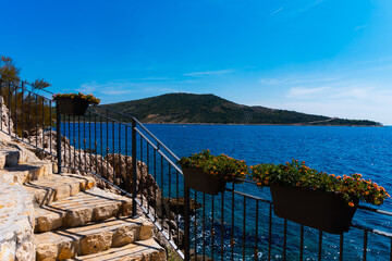 coastline stairway landscape with flower boxes and a beautiful hill in the background in Primosten, Croatia