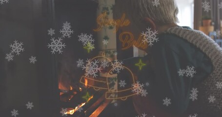Animation of jingle bells text in red neon, christmas bells and snowflakes over boy lighting fire - Powered by Adobe