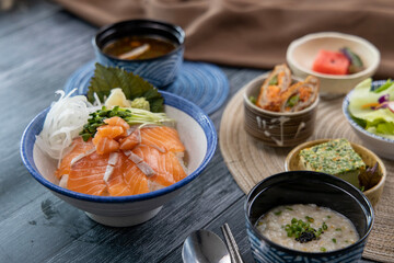 Salmon sashimi on rice and vegetable side dishes 