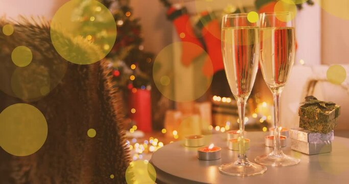 Animation of yellow spots of light over new year glasses of champagne and christmas tree
