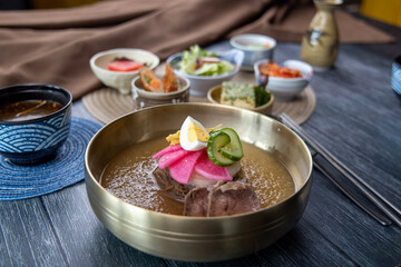 Korean traditional style naengmyeon cold noodles and various fresh vegetable side dishes