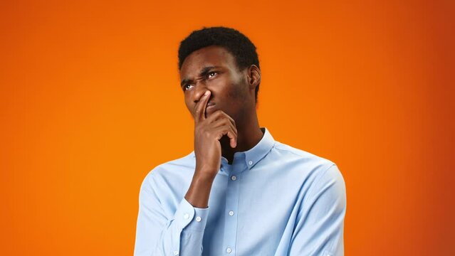 Young african man thinking about something against orange background