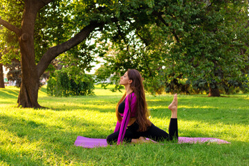 a young woman is doing stretching on a mat in the park. morning meditation in the park