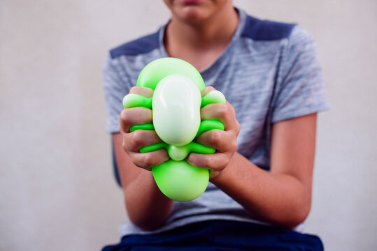 Teen boy playing with anti stress sensory ball squeeze toy. Giant stress balls are soft to the touch and help reduce stress and anxiety as you pull, squish, smash, squash, and grip them in all kinds 