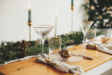 Stylish Christmas table setting. Linen napkin with bell, baubles on plate, vintage cutlery,...