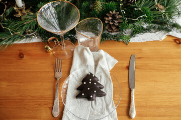 Christmas table setting. Christmas tree cookie on plate, linen napkin with bell, vintage cutlery,...
