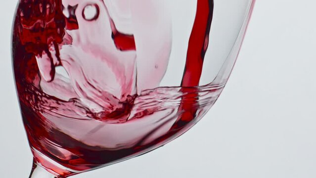 Bubbled red wine beverage closeup. Fresh alcoholic liquid swashing wineglass