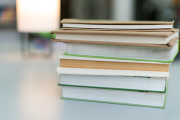 Cropped view of the many stacks of educational books for college exams in the library on a book shelves background. Studying concept