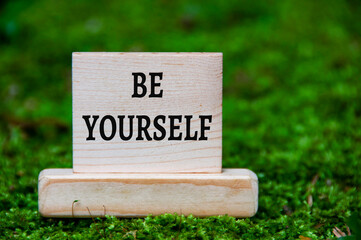 Be yourself text on wooden block with green nature background. Motivational concept