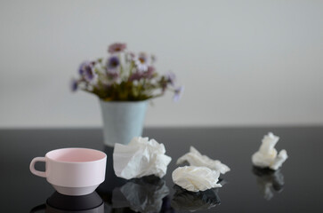 Used tissues on a table with flowers