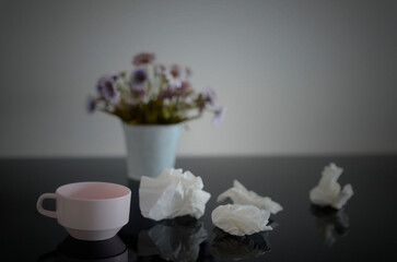 Used tissues on a table with flowers
