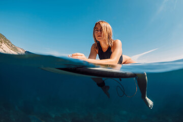 Portrait of blonde surf girl on surfboard in ocean during surfing
