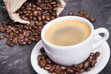 Coffee in white cup and roasted dark coffee beans in bag